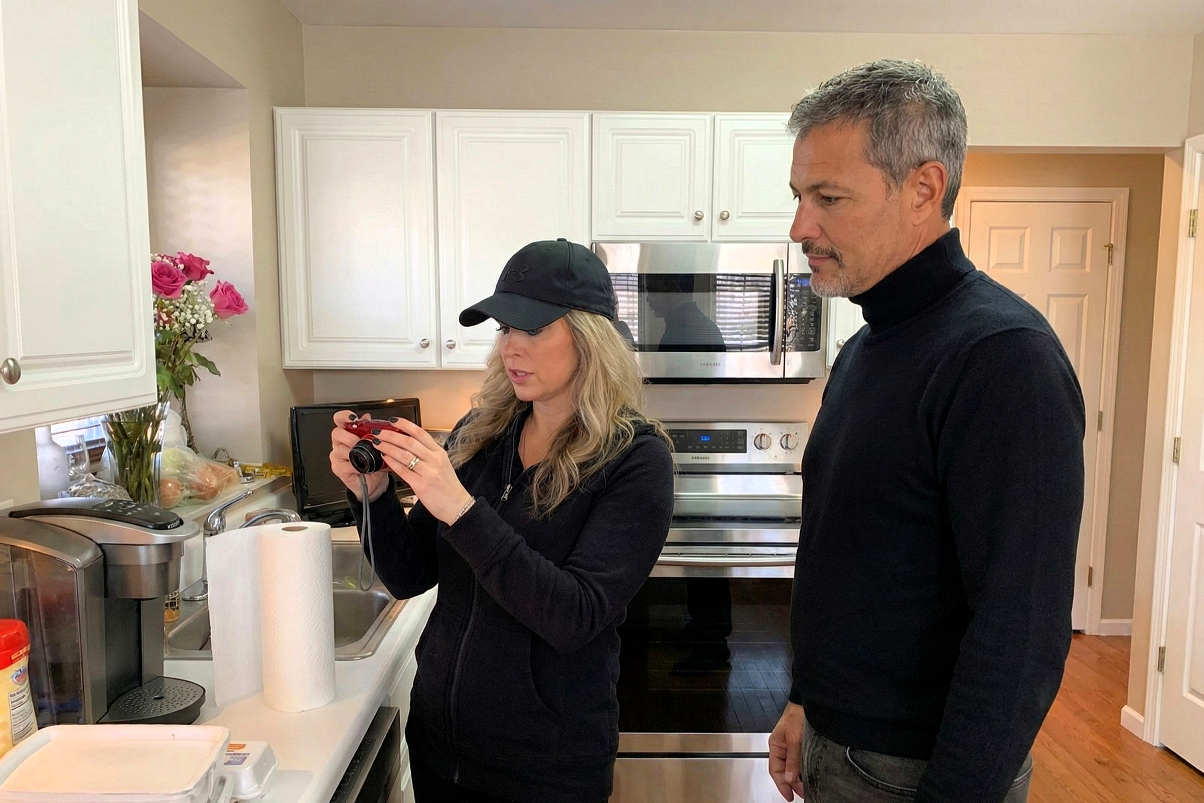Side view of Heather Killebrew and Joey Montes reviewing pictures on a camera in the kitchen at Grover Ridge.