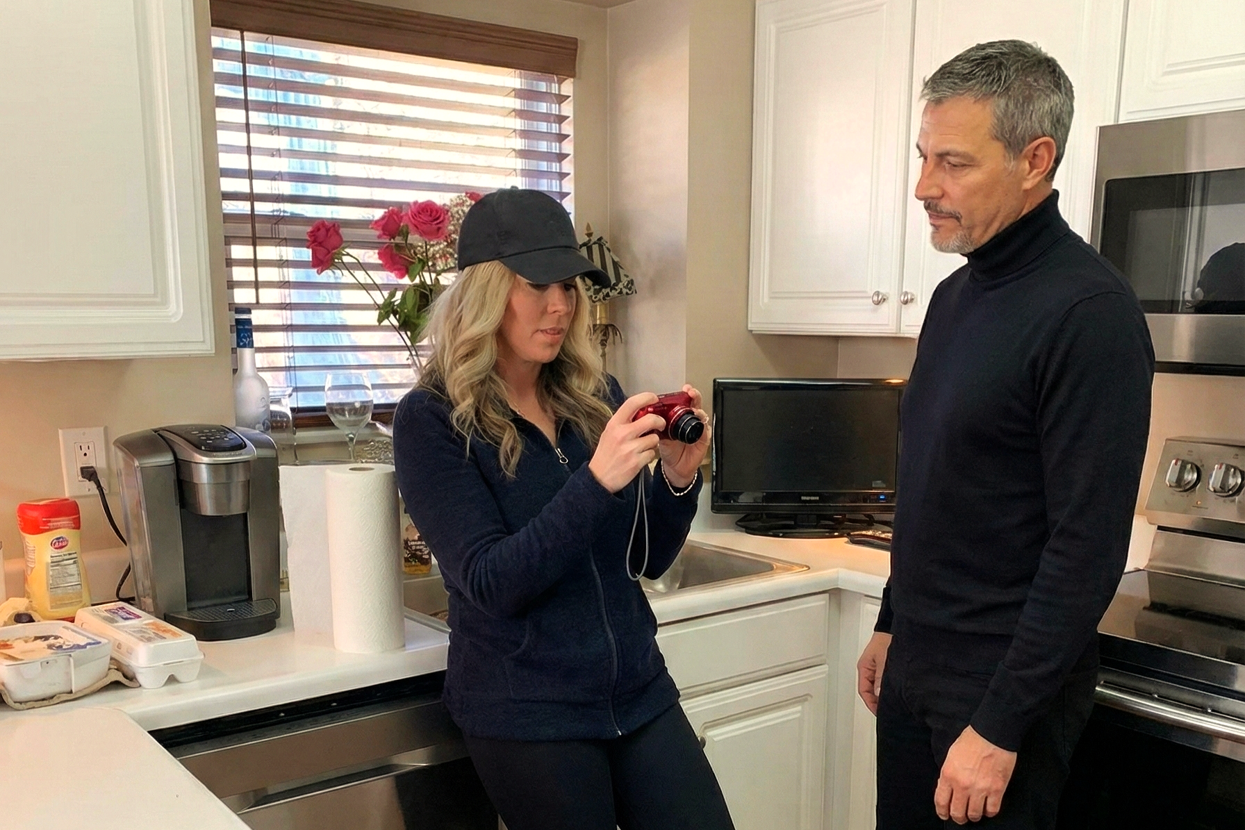 Heather Killebrew reviewing photos on a red camera while Joey Montes looks on in the kitchen at Grover Ridge.
