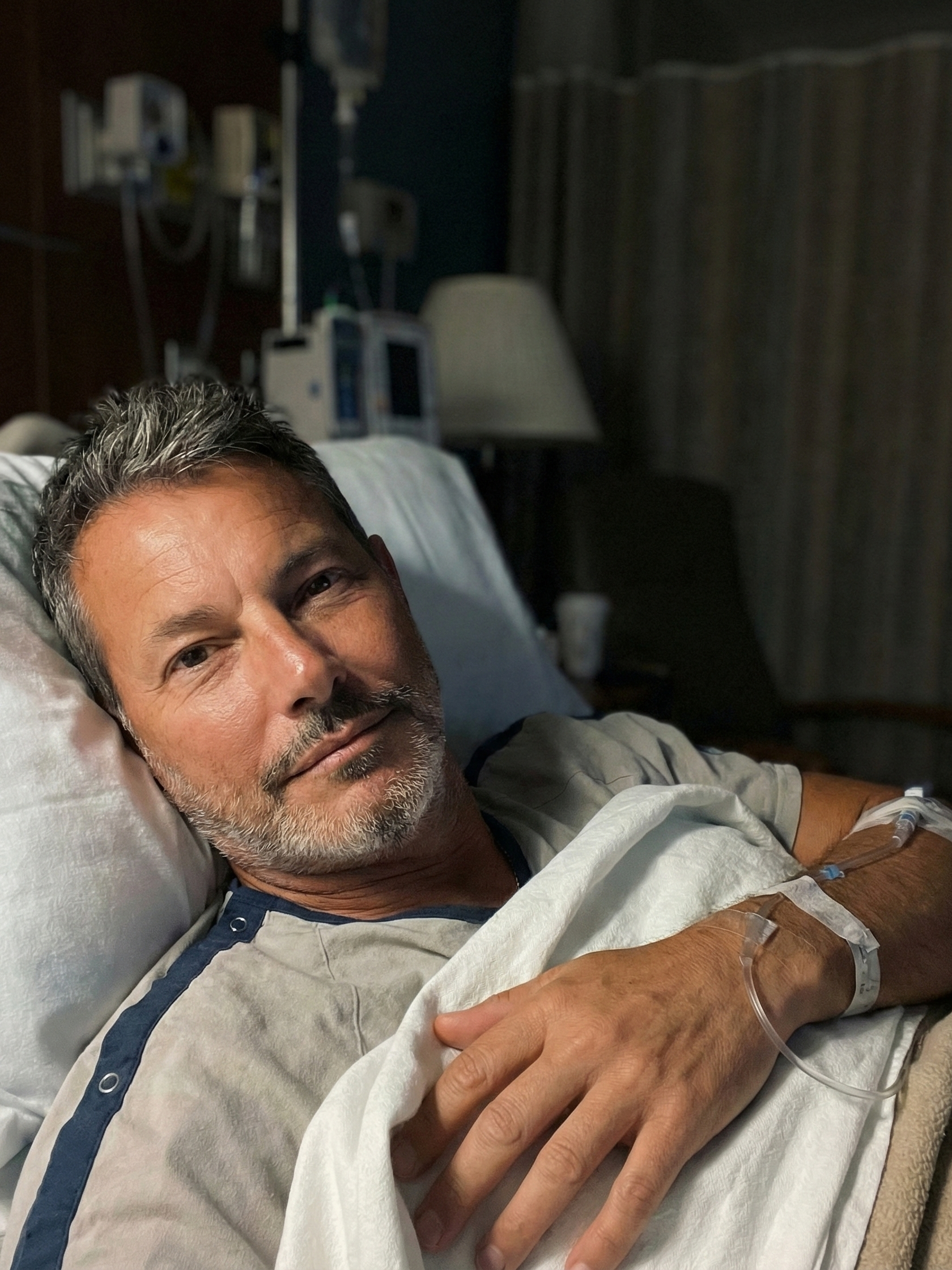 Portrait of Joey Montes lying in a hospital bed, looking at the camera with an expression of endurance.