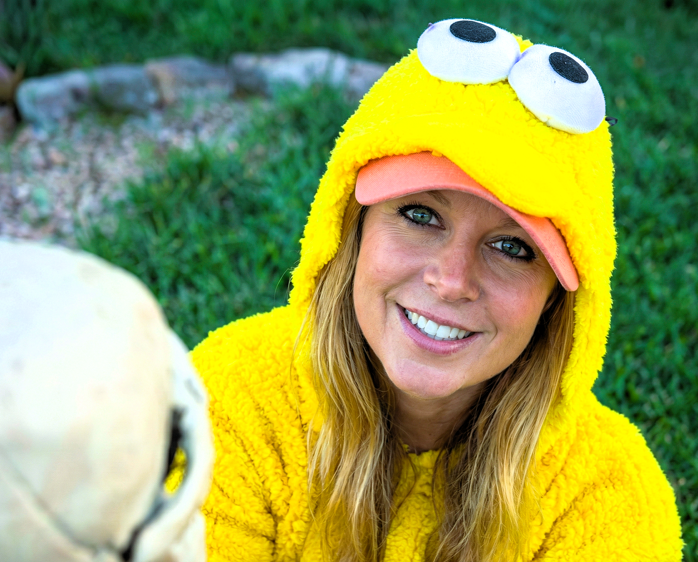 Portrait of Heather Killebrew in a yellow costume smiling brightly next to a skeleton skull.