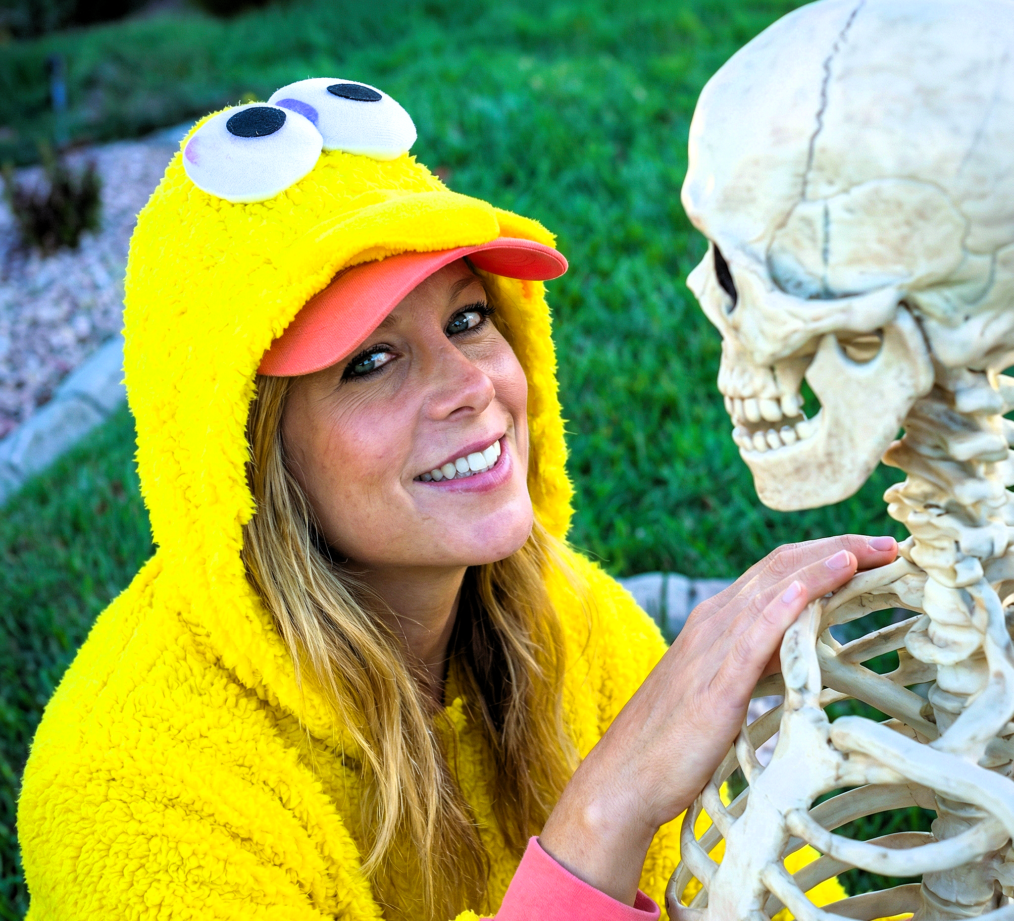 Heather Killebrew resting her hand on the shoulder of a plastic skeleton while wearing a bird costume.