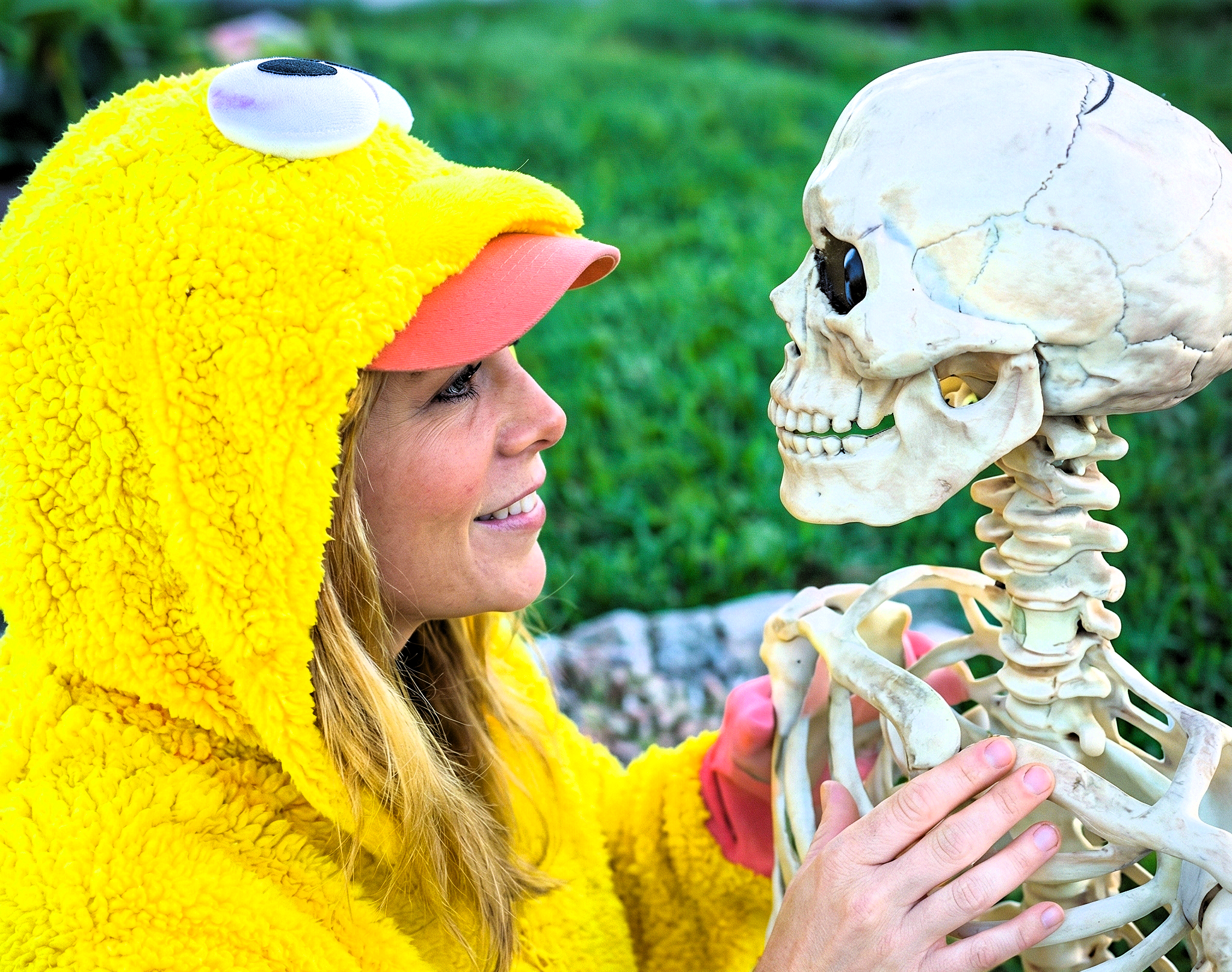 Profile view of Heather Killebrew in a costume staring face-to-face with a plastic skeleton.