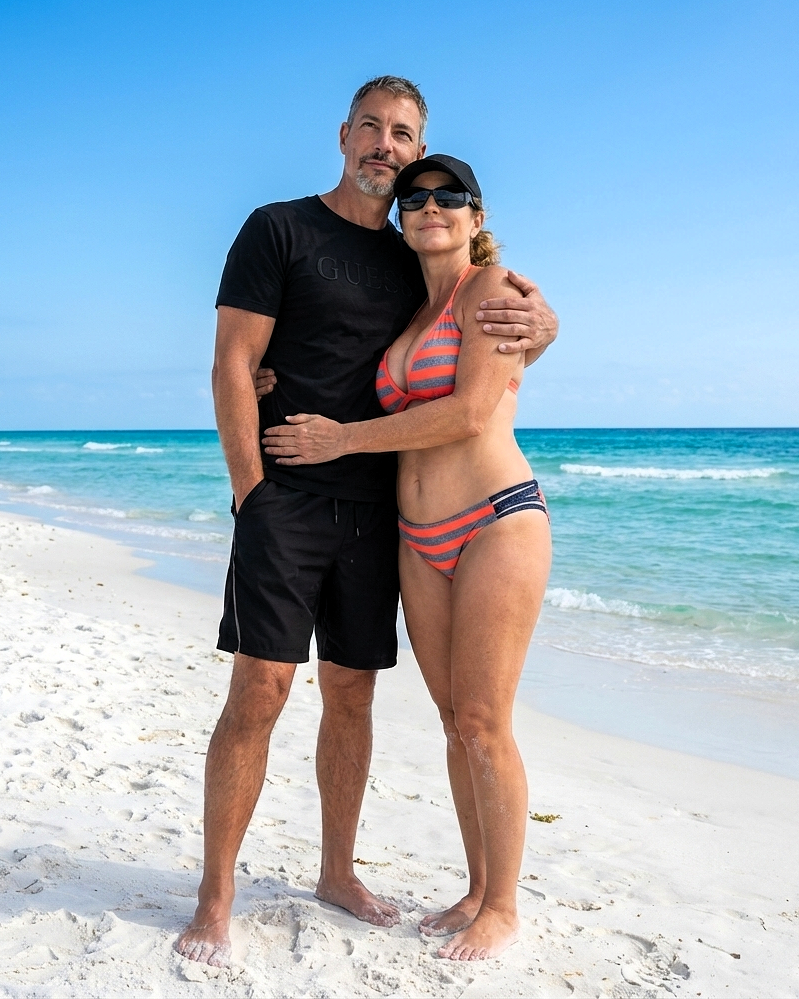 Full-length portrait of Joey Montes and Heather Killebrew standing on the white sands of Destin, FL, with turquoise water in the background.