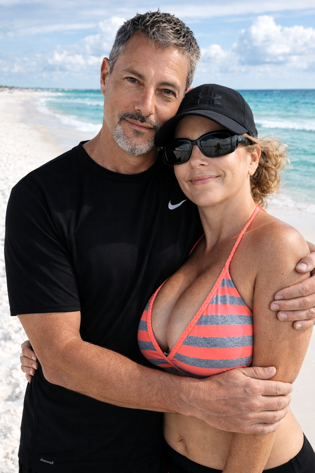 Close-up portrait of Joey Montes in a black Nike shirt and Heather Killebrew hugging on the white sands of Destin.
