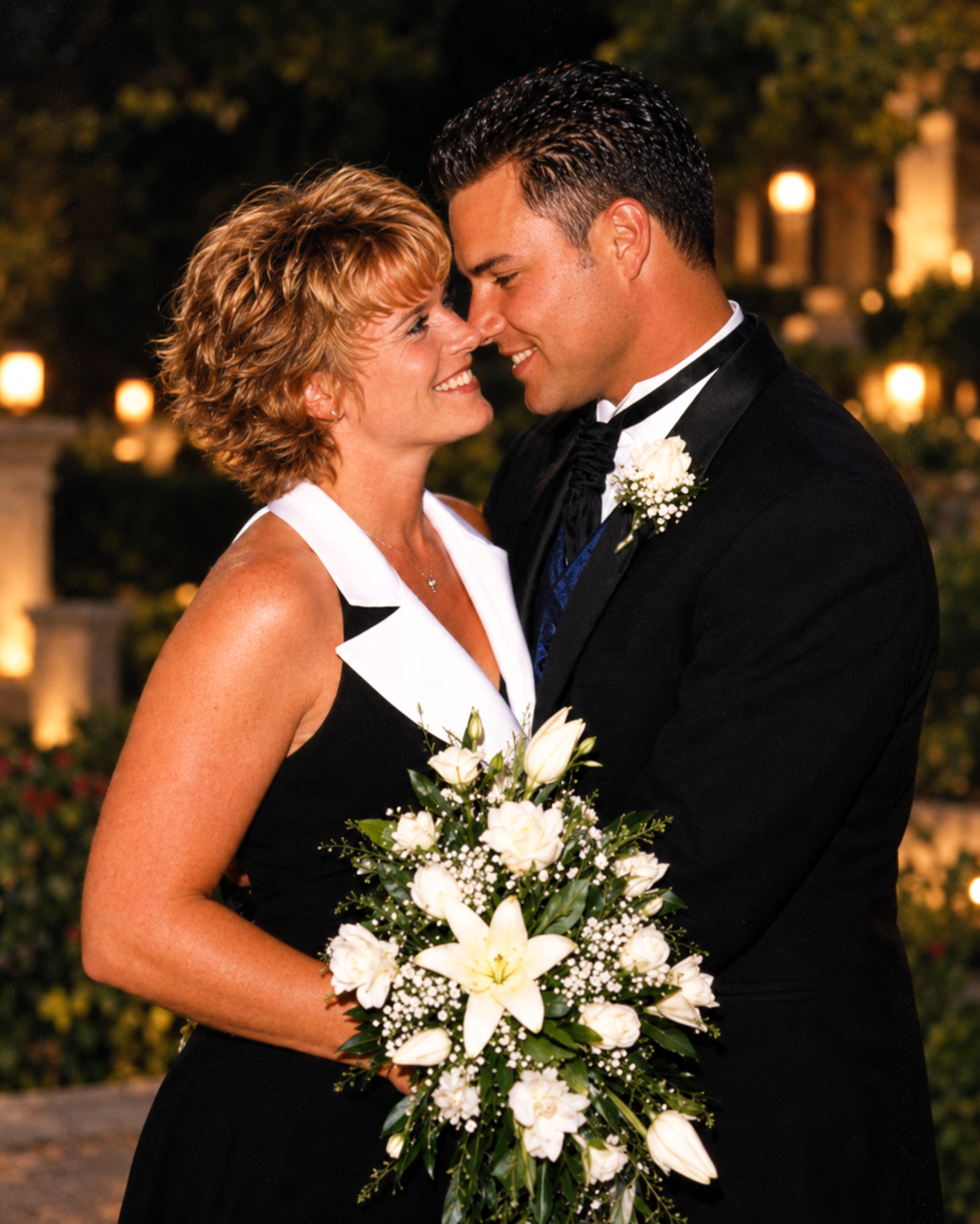 Dawne and Joey sharing a close, smiling moment beside a bouquet of white flowers.