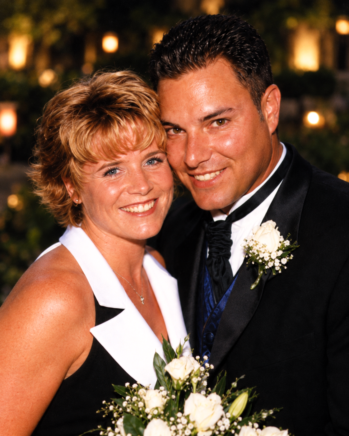 Dawne and Joey smiling close together in formal attire, with white flowers and warm evening lights, July 27, 2001.