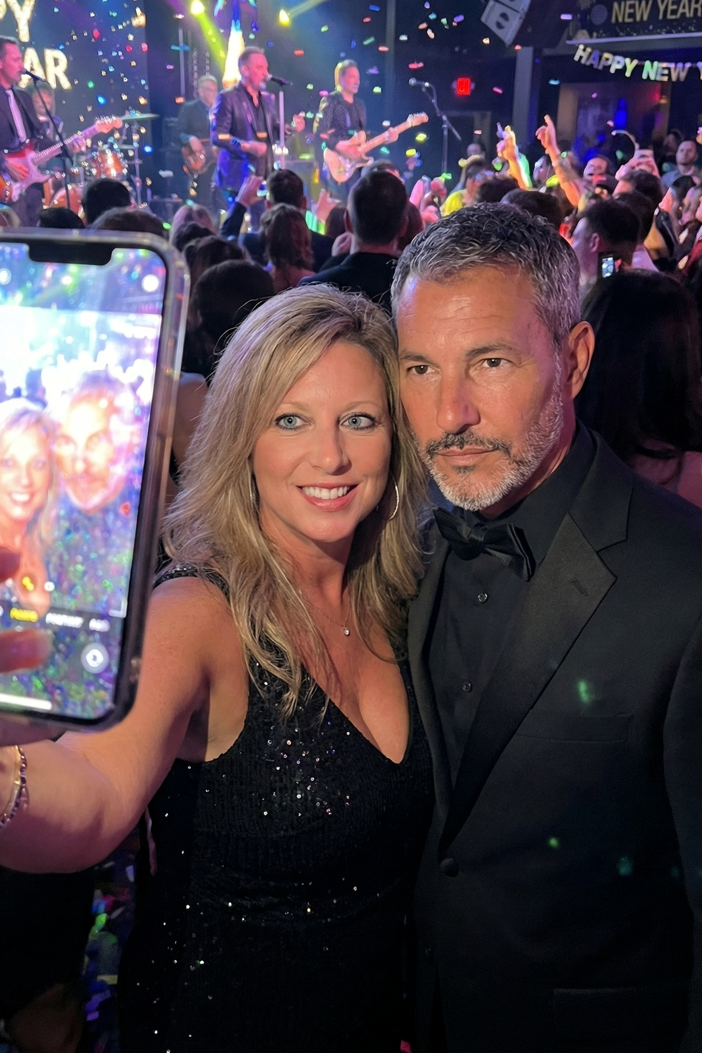 A photo of a smartphone screen displaying a selfie of Heather Killebrew and Joey Montes at a party with purple lighting.