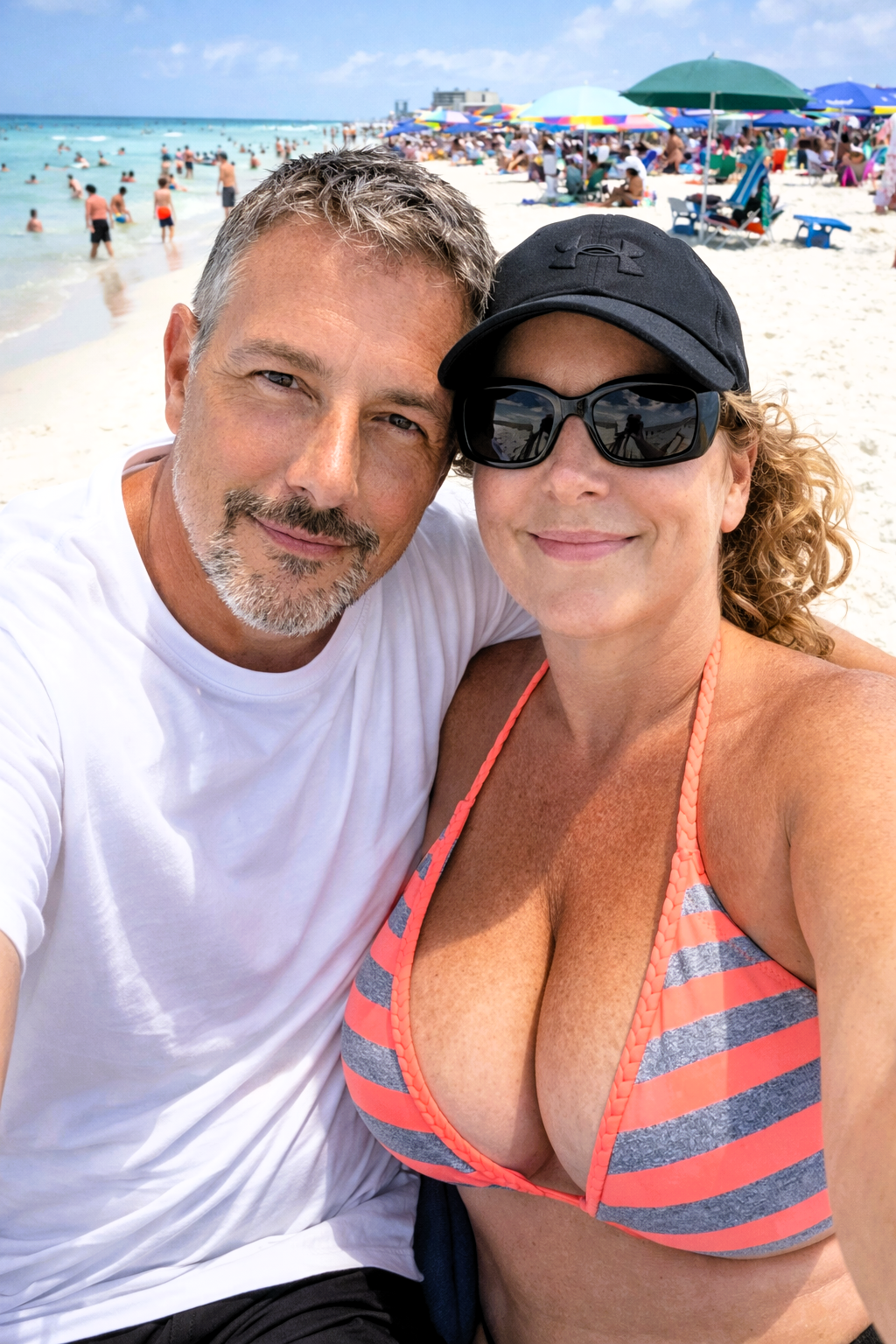 Close-up selfie of Joey Montes (in a white t-shirt) and Heather Killebrew smiling on the beach.