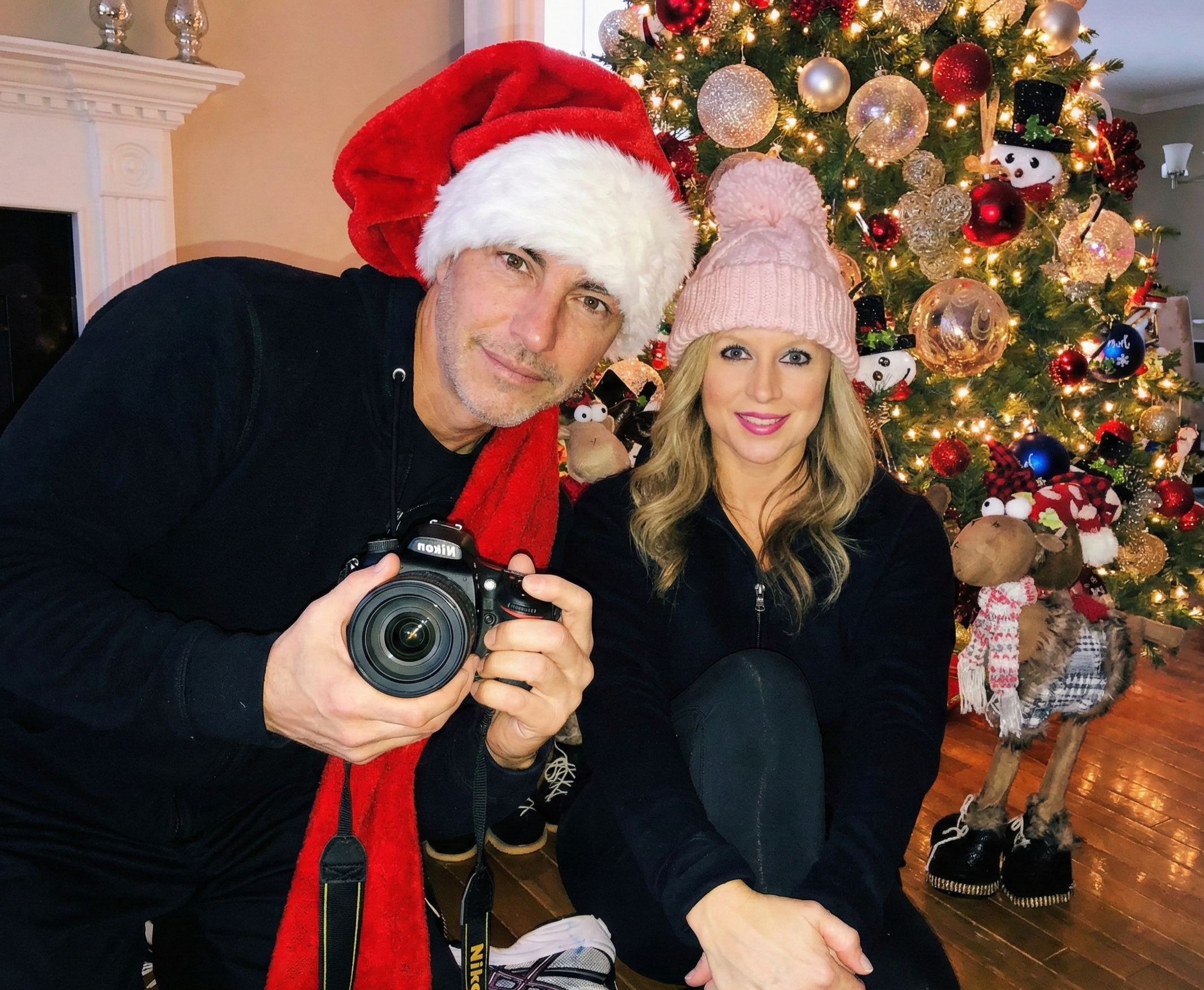 Mirror selfie of Joey Montes holding a camera and Heather in a pink beanie sitting by a Christmas tree in Wildwood, 2018.