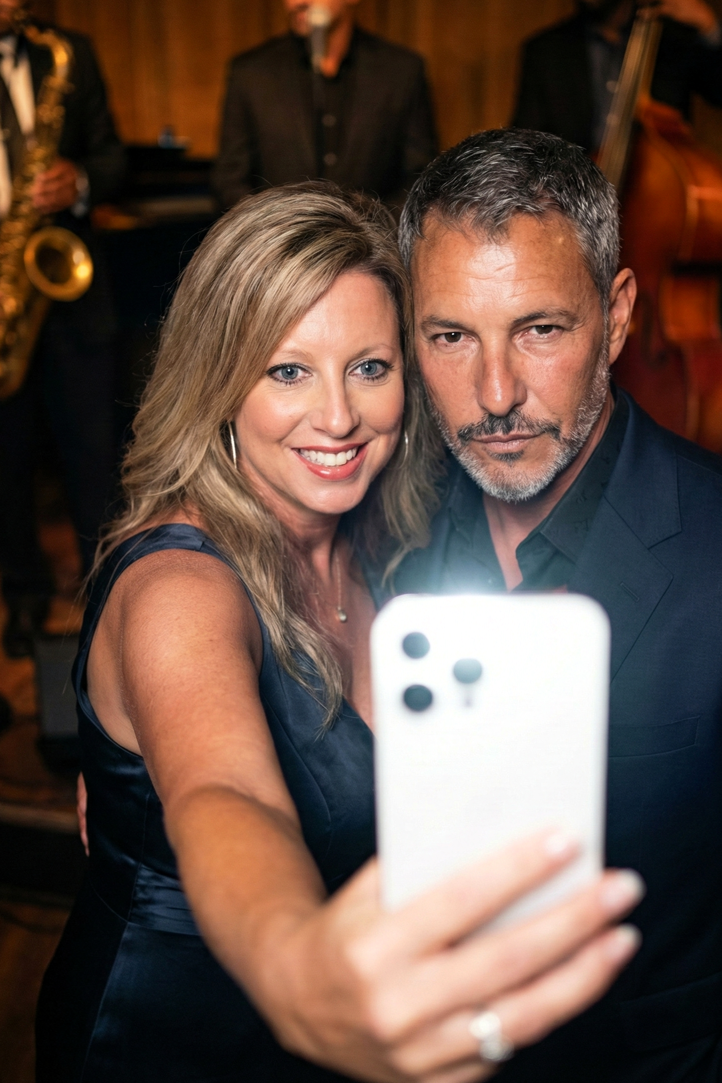 Cinematic shot of Heather Killebrew holding up a phone to take a selfie with Joey Montes in a jazz club.