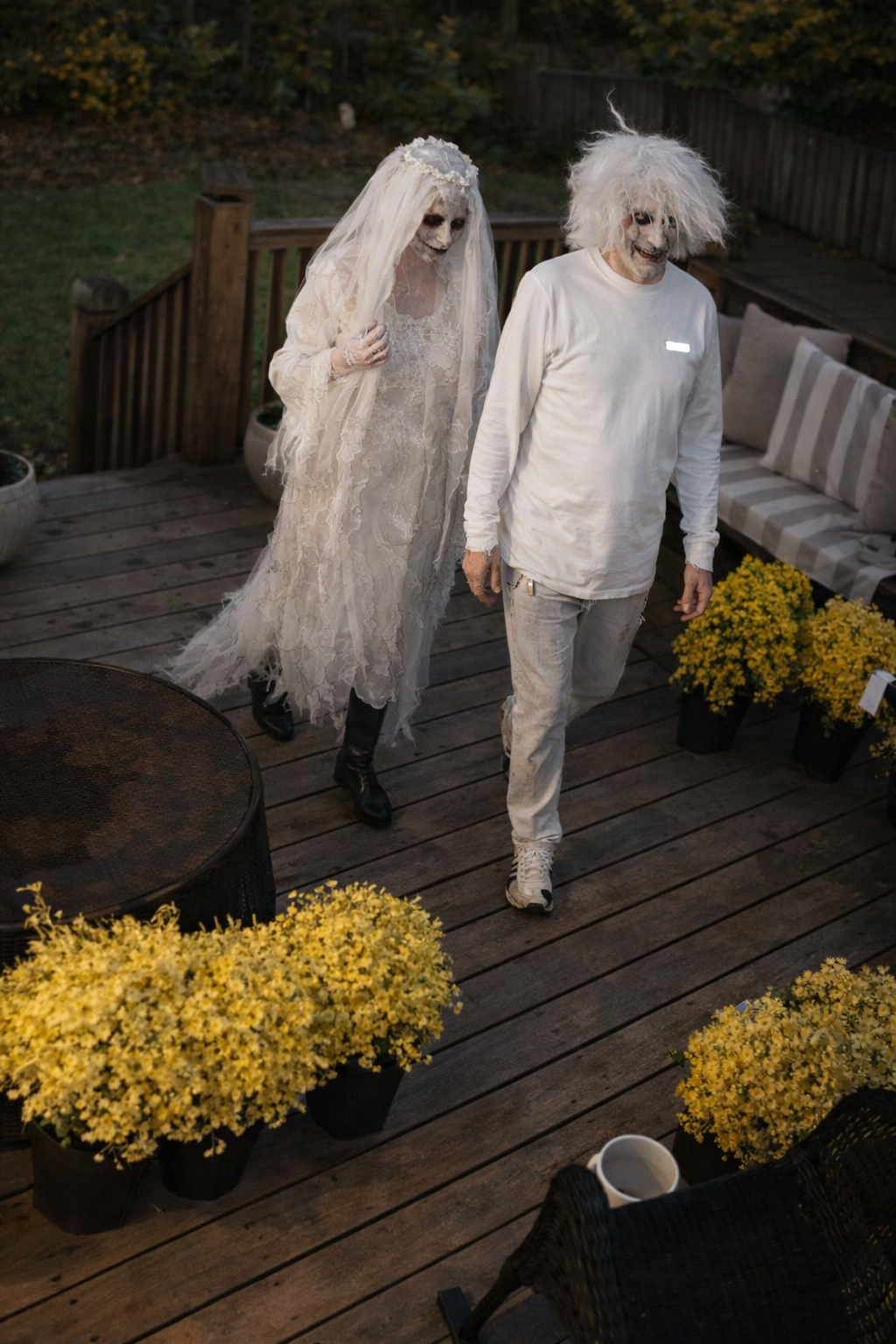 Another angle of the ghostly couple walking through yellow mums on Halloween 2021.