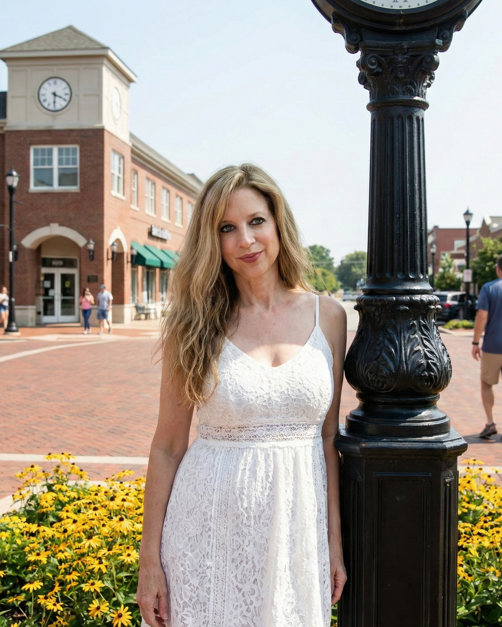Portrait of Heather Killebrew in a white lace dress standing by a clock tower in Wildwood.