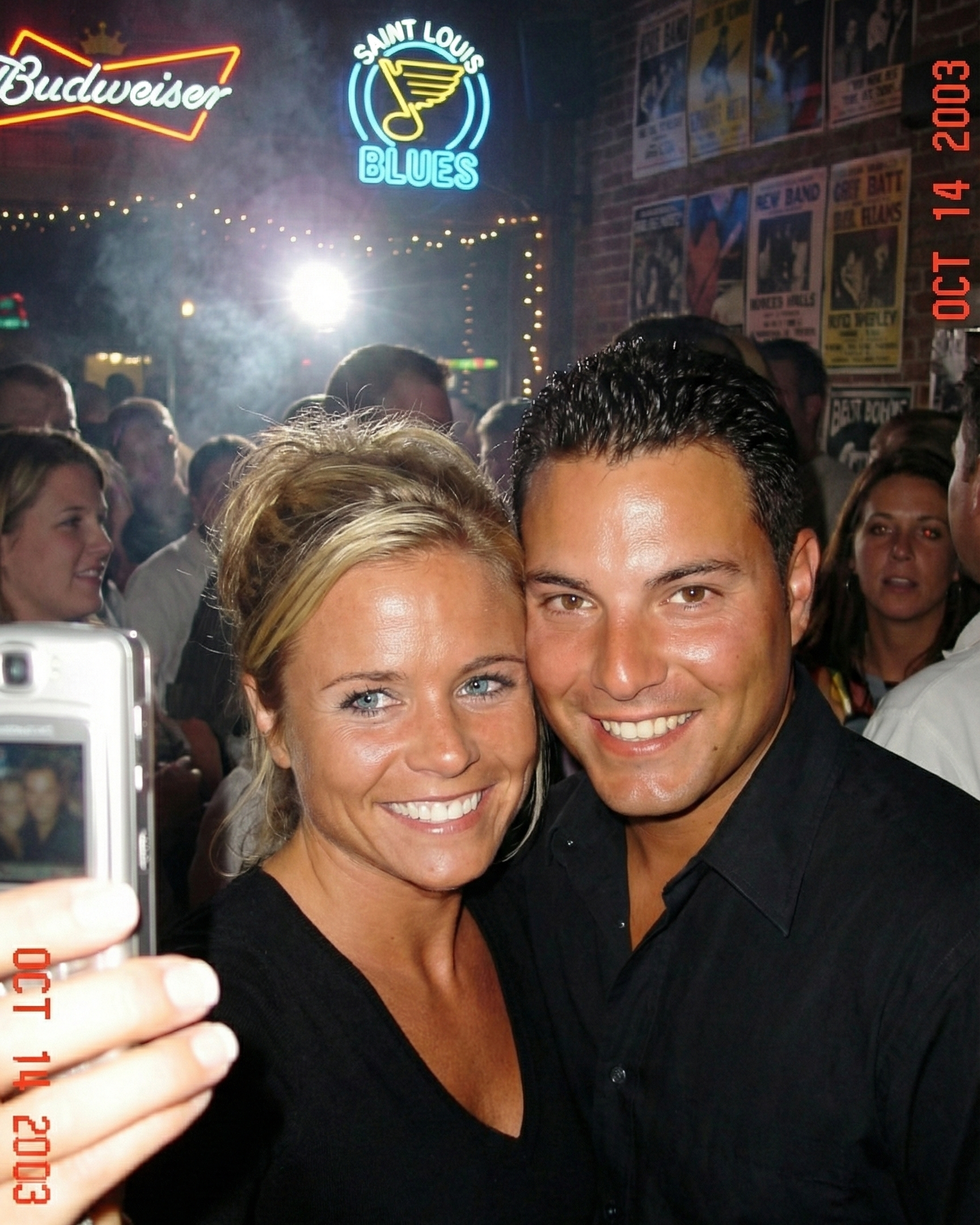 Joey and Dawne taking a selfie in a crowded St. Louis bar with a Blues neon sign in 2003.