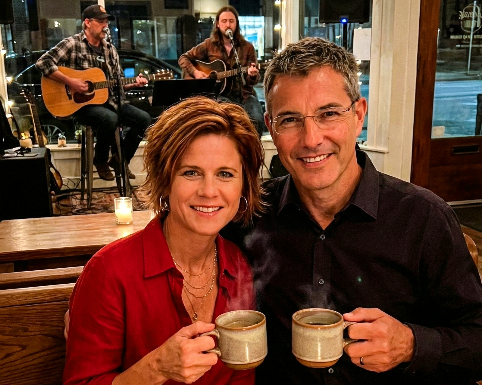 Joey Montes and Dawne holding steaming mugs of coffee while sitting in front of an acoustic band.
