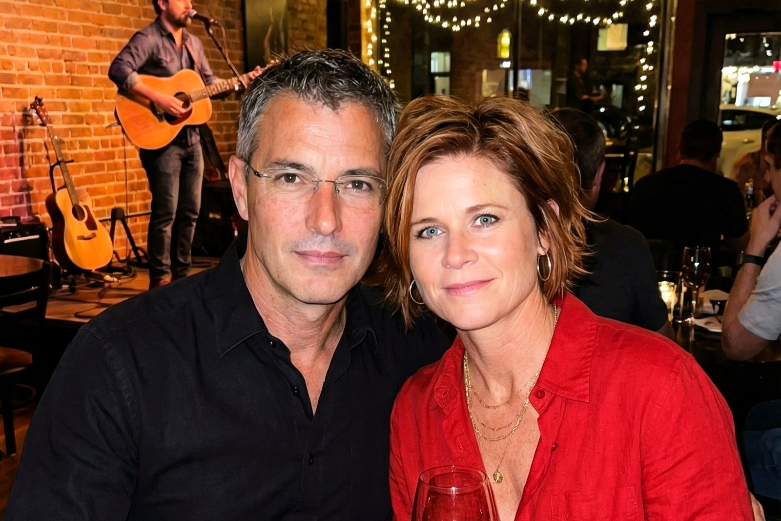 Portrait of Joey Montes and Dawne smiling together during a night out with live acoustic music.