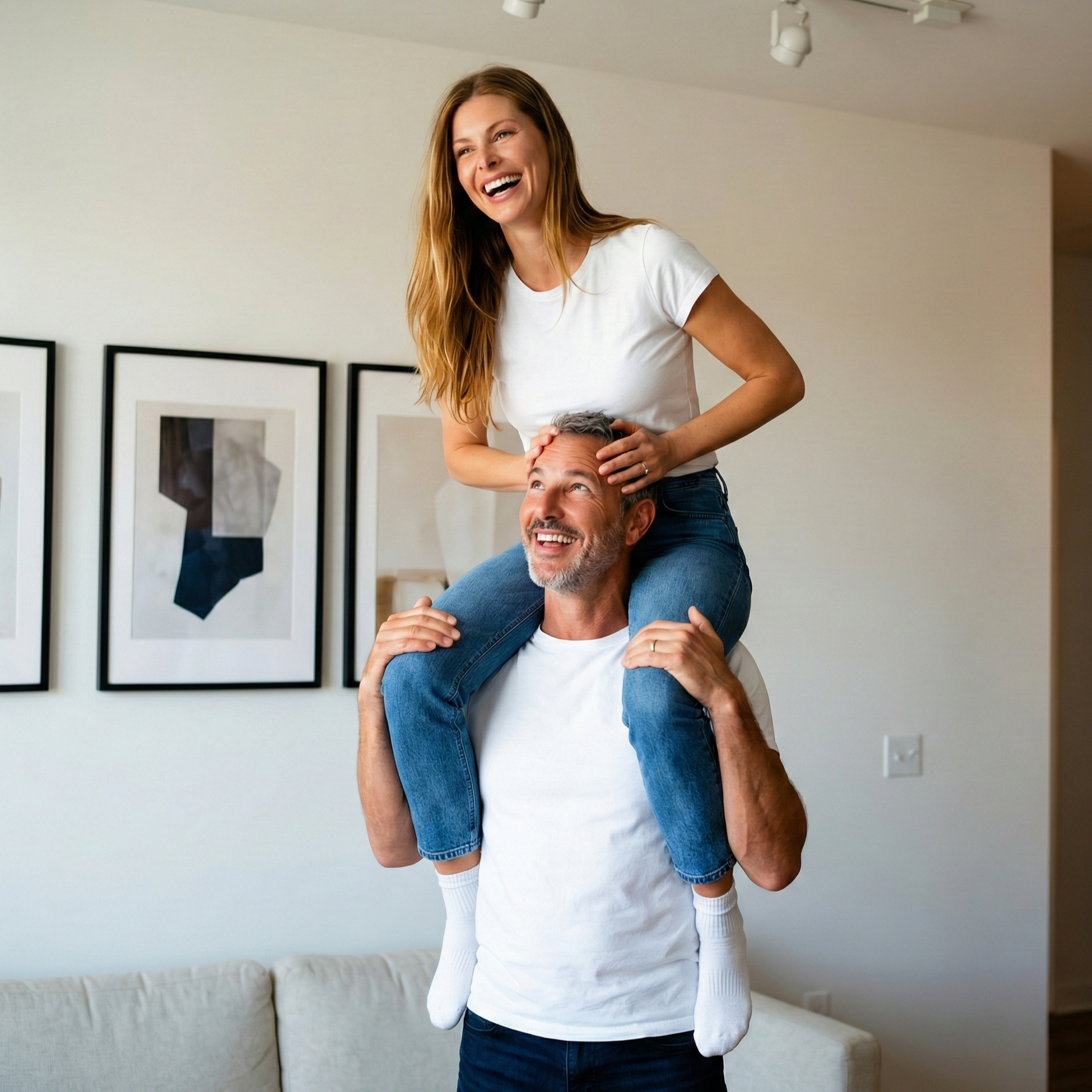 Joey Montes giving a female friend a ride on his shoulders in a living room, both laughing and wearing white t-shirts.