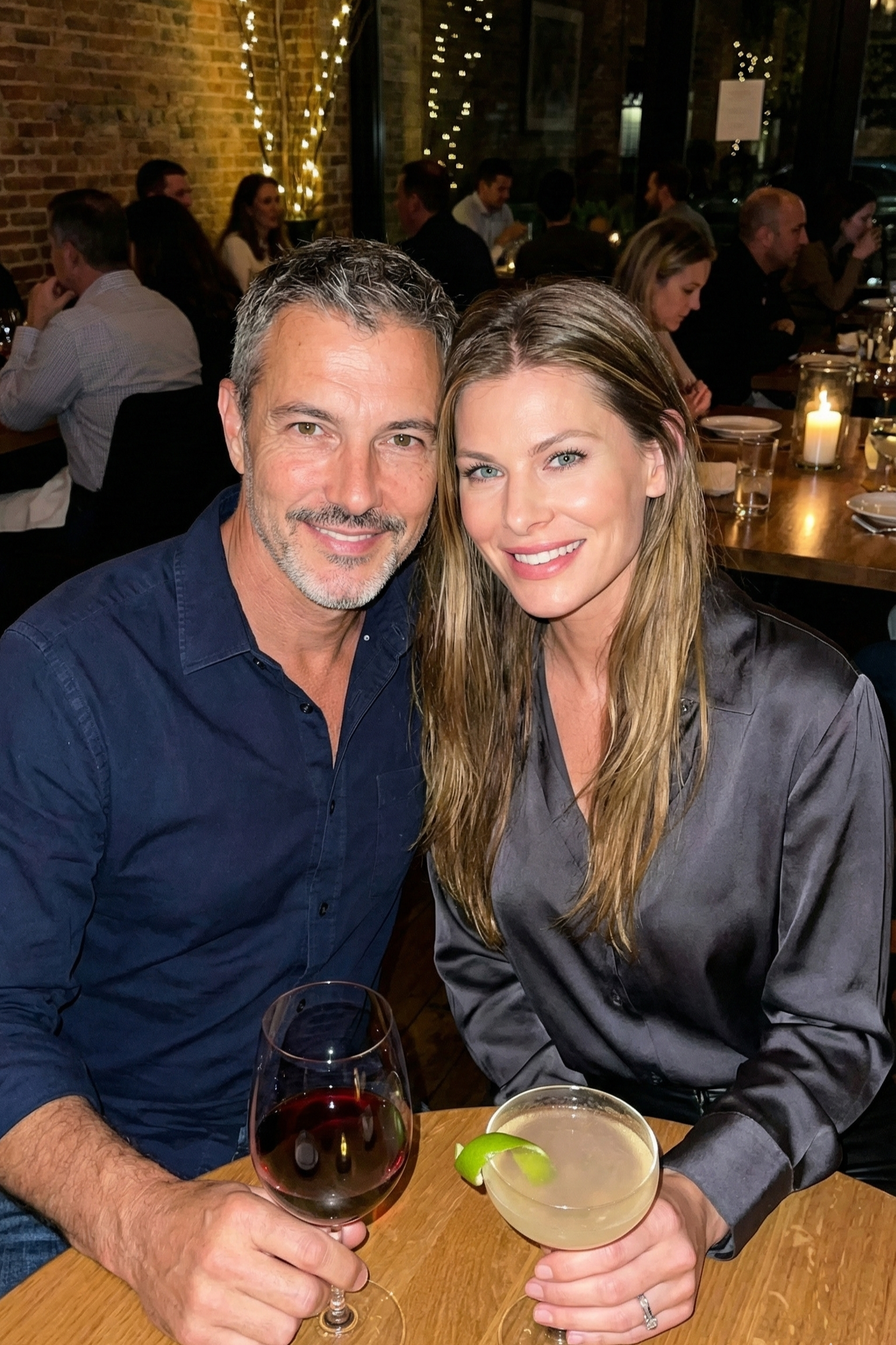 Joey Montes and a female friend smiling at a restaurant table with drinks, celebrating a night out.